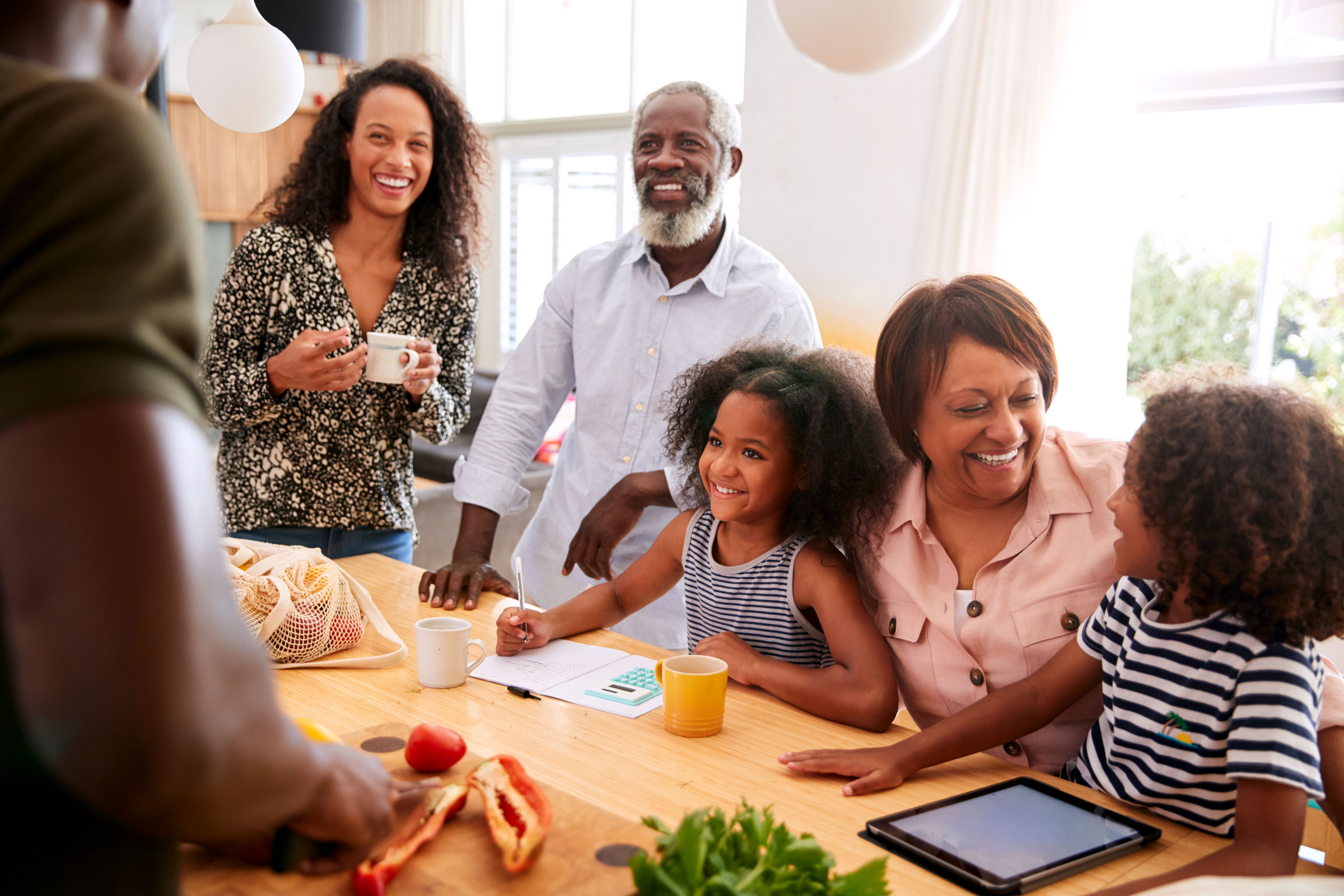 Multigenerational Black family laughing together at the dinner table, illustrating how to protect your mental health by setting boundaries at home.