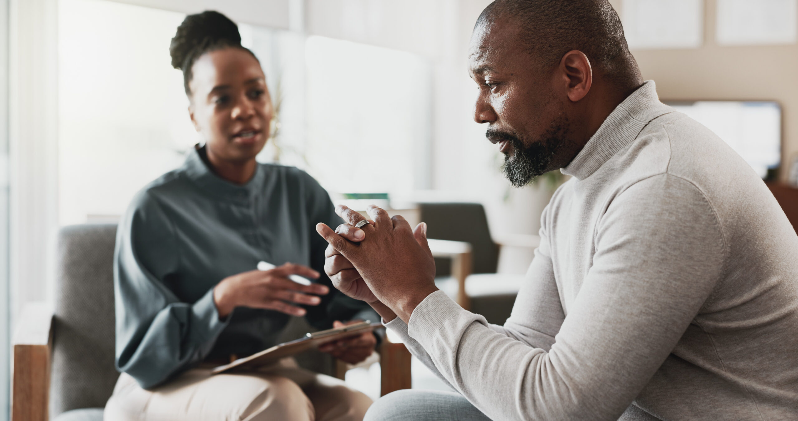 Black male therapist speaking with a Black female patient during a counseling session, representing culturally competent mental health resources Alameda County residents can trust.