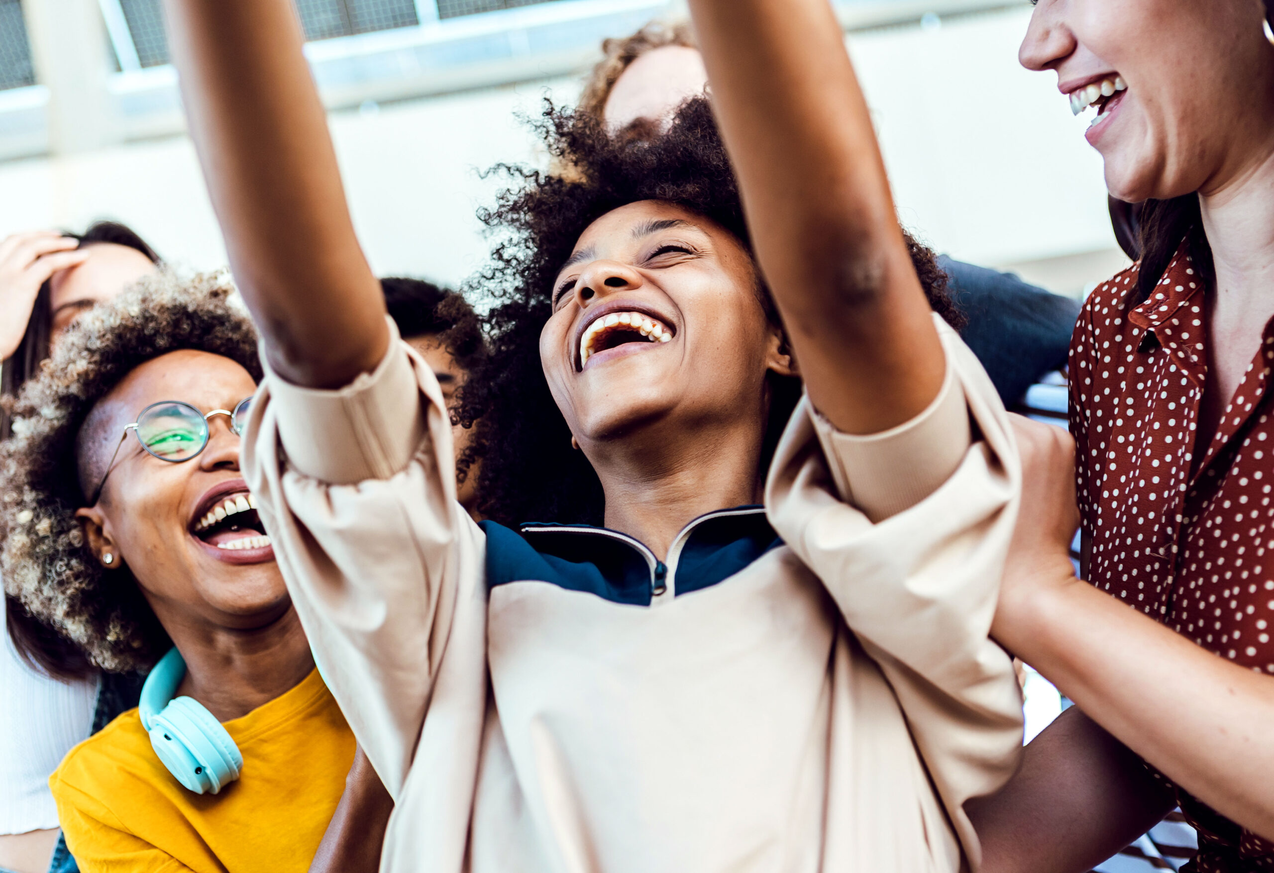 A black child raises his hands and shows a joyous expression with friends and family.